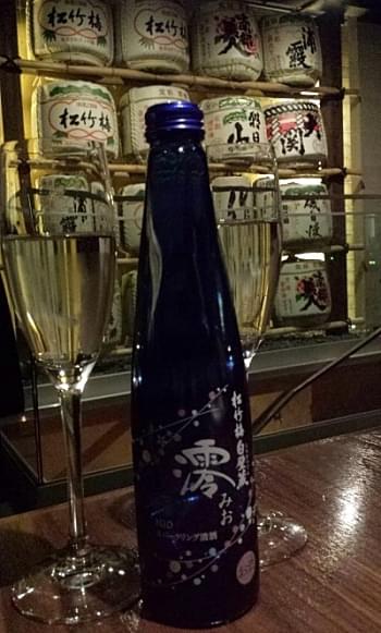 A bottle of sake and a glass sitting on a restaurant table